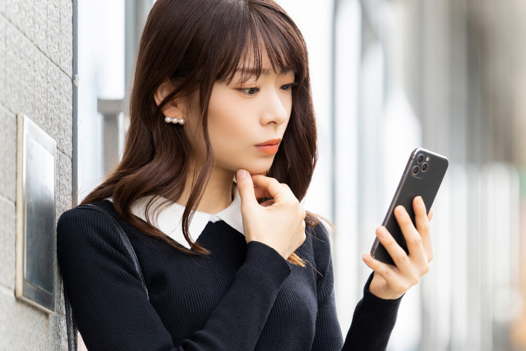 スマホを見て考える女性